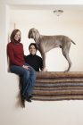 Lesbian couple posing with Weimaraner dog in wall niche. — Stock Photo