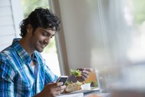 Mann checkt Handy beim Essen im Café. — Stockfoto