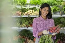 Young woman holding bunch of red beets at farmer store. — Stock Photo