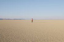 Man walking across flat desert landscape — Stock Photo