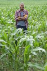 Молодий чоловік з обіймами схрестив стоячи на полі кукурудзи на органічній фермі . — стокове фото