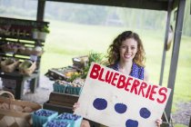 Woman carrying blueberries sign on organic farm. — Stock Photo