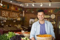 Man holding bowl of freshly picked tomatoes at farmer store. — Stock Photo