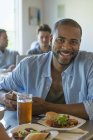 Hombre sonriendo y mirando en la cámara en la mesa del café con un vaso de cerveza . - foto de stock