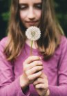 Teen girl holding dandelion seed head on long stem. — Stock Photo