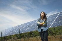 Junge Frau steht vor Solaranlage auf Bauernhof im Grünen. — Stockfoto