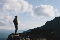Escursionista maschio in piedi sulla scogliera rocciosa al crepuscolo — Foto stock