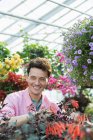 Mid adult man checking and tending flowers in greenhouse of plant nursery. — Stock Photo