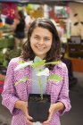 Young woman holding plant in pot at farmer market stand. — Stock Photo