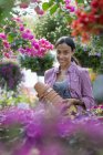 Молодая женщина несет стопку горшков в цветочный питомник . — стоковое фото