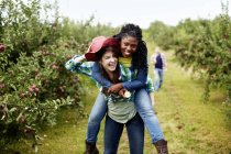 Young woman giving friend piggyback on countryside road. — Stock Photo