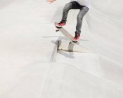 Cropped view of skateboarder standing on board in red trainers. — Stock Photo