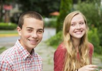 Junge und Mädchen im Teenageralter sitzen nebeneinander und lachen. — Stockfoto