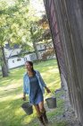 Woman carrying buckets by country barn at farm. — Stock Photo