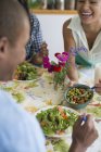 Woman laughing and sharing salad with friends in country kitchen interior. — Stock Photo