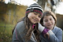 Elementary age girls leaning on fence post in countryside. — Stock Photo