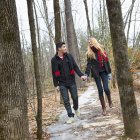 Casal caminhando de mãos dadas através da floresta no inverno . — Fotografia de Stock