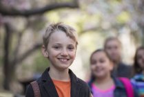 Blond boy and group of pre-adolescent children standing on sidewalk. — Stock Photo
