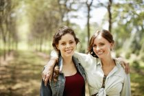 Female friends smiling and embracing on country road. — Stock Photo