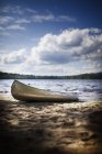 Bateau de canot échoué sur le rivage du lac dans la forêt avec paysage nuageux pittoresque . — Photo de stock