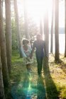 Jovem casal caminhando na floresta pela margem do lago . — Fotografia de Stock