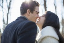 Young couple kissing and laughing in woods in winter. — Stock Photo