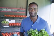 Mann trägt grünes Gemüse in Bioladen. — Stockfoto
