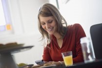 Jovem mulher usando smartphone enquanto se senta à mesa no café . — Fotografia de Stock
