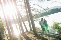 Couple walking hand in hand in woodland on shore of forest lake. — Stock Photo