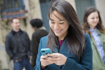 Жінка перевіряє бірюзовий смартфон серед людей на міській вулиці . — стокове фото