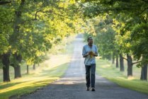 Man walking down avenue in countryside park. — Stock Photo