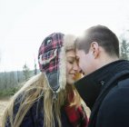 Молодая пара, стоящая лицом к лицу и обнимающаяся в зимнем лесу . — стоковое фото