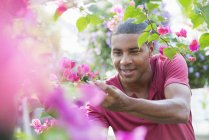 Середній дорослий чоловік перевіряє і доглядає квіти в теплиці розплідника рослин . — стокове фото