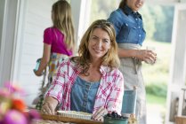 Mid adult woman cooking at outdoor table with family on farmhouse terrace. — Stock Photo