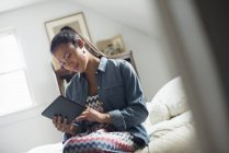 Young woman using digital tablet on bed indoors. — Stock Photo