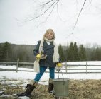 Ragazza in età elementare che trasporta secchio di metallo nella neve . — Foto stock