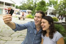 Jeune couple debout côte à côte et prendre selfie dans la rue . — Photo de stock
