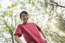 Vue à faible angle du garçon pré-adolescent posant dans les bois . — Photo de stock