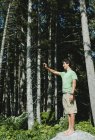 Мальчик-подросток, стоящий в лесу и делающий селфи со смартфоном в Олимпийском национальном парке, Вашингтон, США — стоковое фото