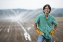 Молодий фермер у робочому одязі на органічному полі з зрошувальними водорозбризкувачами . — стокове фото