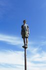 Homme équilibrage sur poteau métallique contre ciel bleu avec des nuages . — Photo de stock