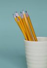 Sharpened pencils in cup on blue background. — Stock Photo