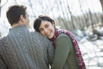 Young couple hugging outdoors in wintry woods. — Stock Photo