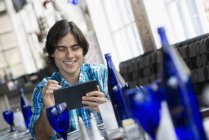 Hombre joven sentado en la mesa en la cafetería y el uso de tableta digital . - foto de stock