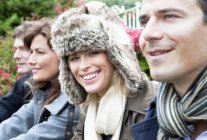 Four people outdoors in coats and scarves. — Stock Photo