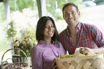 Man and woman holding basket of organic beans at farmer market stand. — Stock Photo