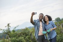 Couple taking selfie with smartphone while blackberry picking. — Stock Photo