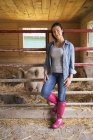 Woman standing beside pigs in pen at farm. — Stock Photo