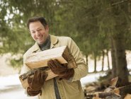 Mature man posing with wood logs in countryside. — Stock Photo