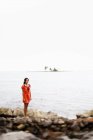 Frau in rotem Kleid steht am Strand in Las Galeras, Samana Halbinsel, Dominikanische Republik. — Stockfoto
